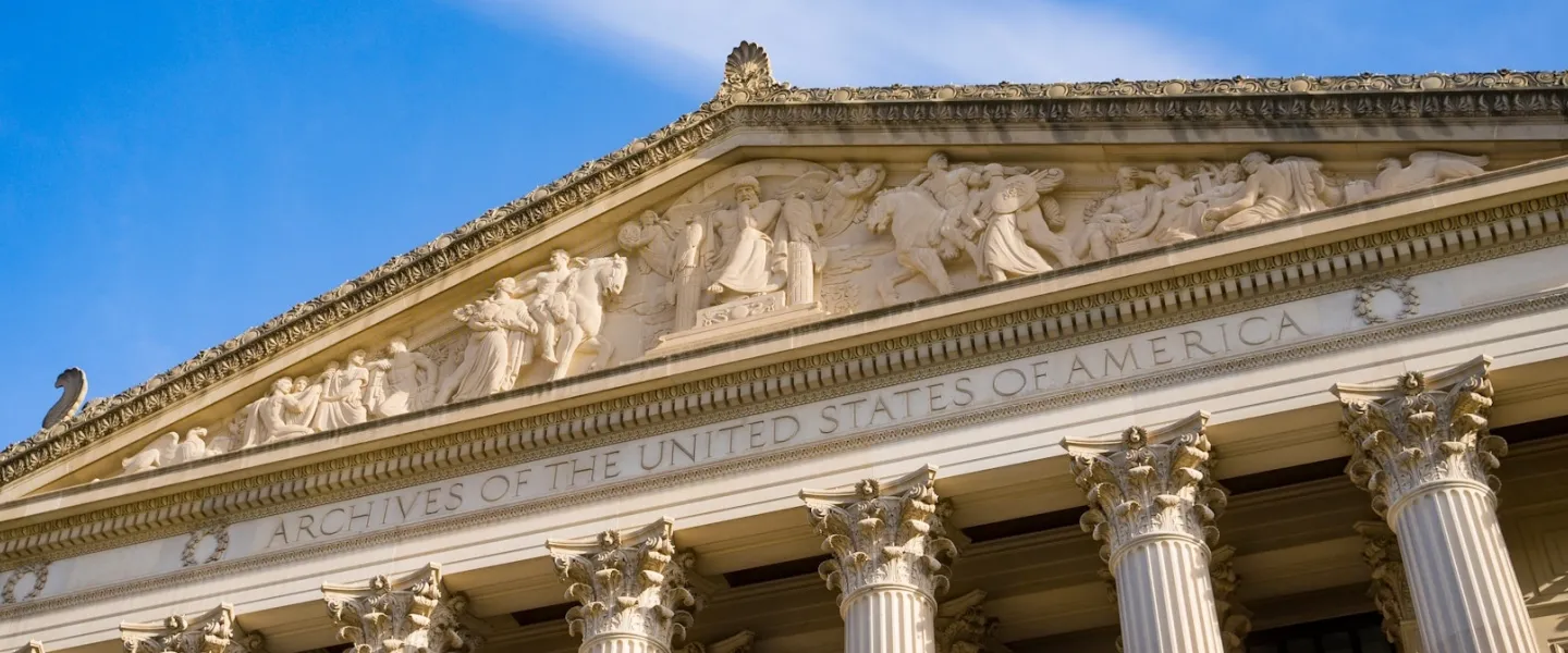 Close-up photo of neoclassical building pediment and columns against blue sky