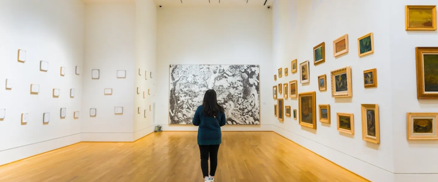 Person walking through bright art gallery in The Phillips Collection with framed works on white walls