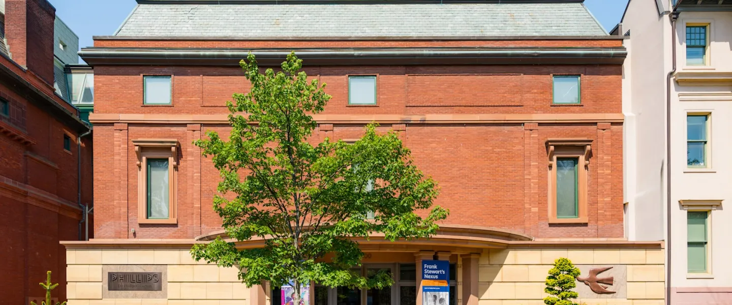 The Phillips Collection, a red-brick building with blue awnings and a street tree on a sunny day