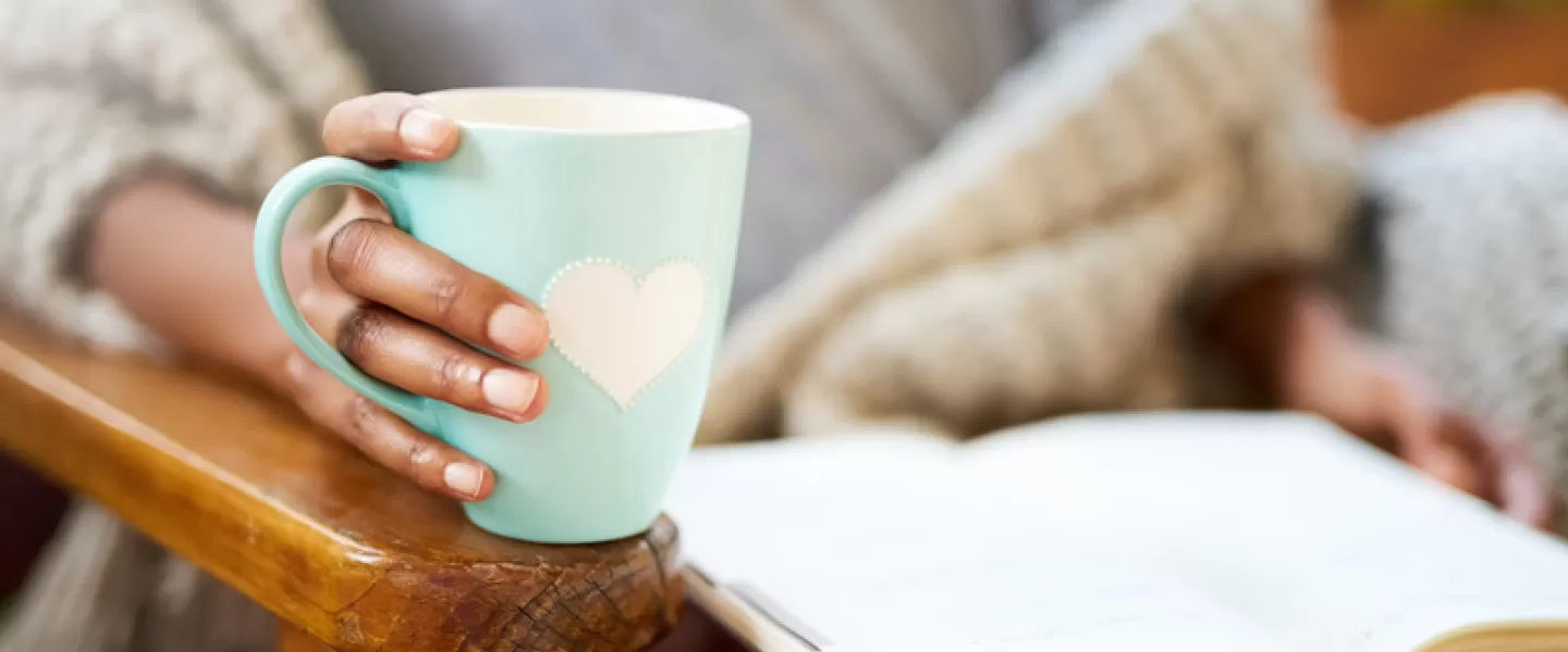 Mujer sosteniendo la taza y leyendo un libro