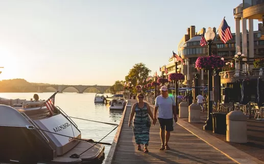 Casal caminhando ao longo do Washington Harbor Georgetown Waterfront ao pôr do sol em Washington, DC