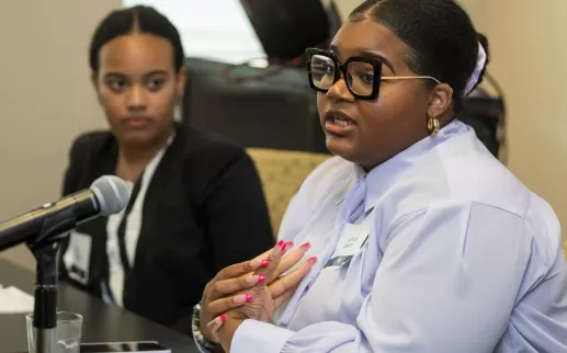 Two young Black women - Zoe Roberts & Cayla Lewis - speak on a professional conference panel
