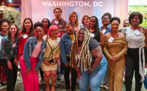 Um grupo de jovens adultos sorridentes diante de uma faixa onde se lê Washington, DC