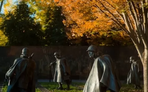 Several figures from the Korean War Veterans Memorial with autumn trees.