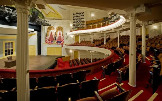 The historic Ford's Theatre features elegant red seating, curved balconies, and a stage framed by rich gold accents.