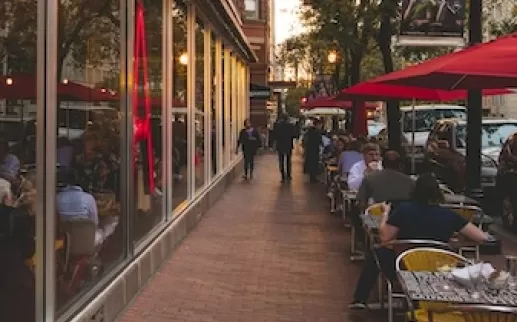 De buitenkant van Jaleo by José Andrés in Washington, DC, met grote rode neonletters en zitplaatsen buiten onder rode parasols.