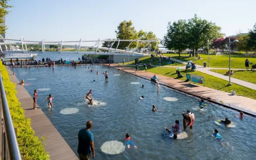 Kids play in a massive splash pool at a public park in the summertime. 