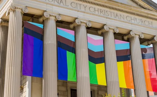 The columns of a historic church decorated with LGBTQIA+ flags.
