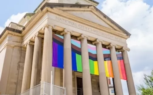 The columns of a historic church decorated with LGBTQIA+ flags.