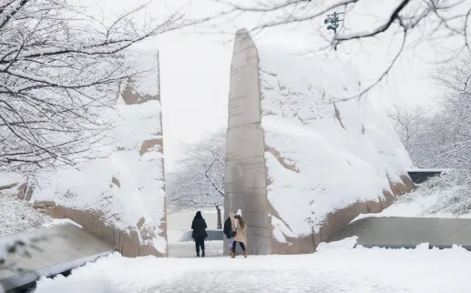 Visitors walk through the snow-covered entrance stones at the Martin Luther King, Jr. Memorial in Washington, DC surrounded by frosted trees after a winter snowfall.