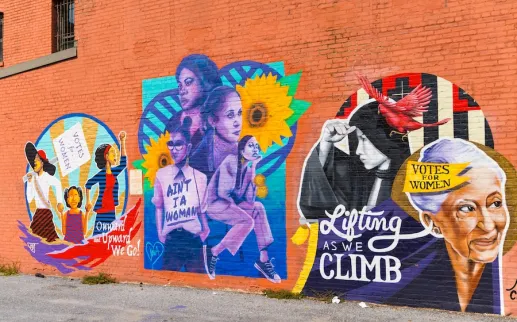 A colorful mural depicting three scenes of women's suffrage and empowerment.
