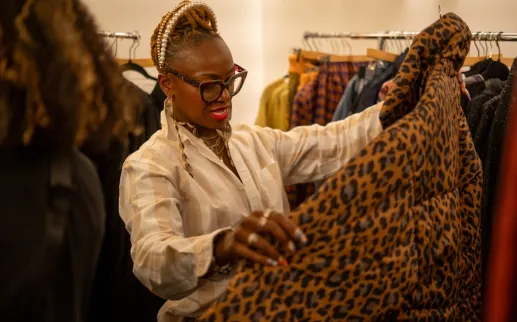A shopper examines a patterned garment inside a stylish clothing boutique.
