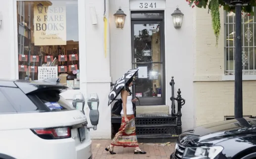 Storefront entrance with scooters parked outside, cars along the street