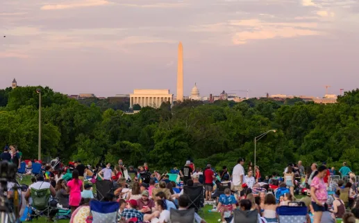 Crowd picnicking at sunset with the Washington Monument in the distance