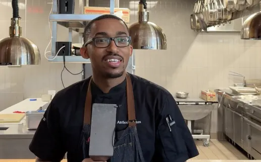 Chef in an apron holding a microphone in a restaurant kitchen
