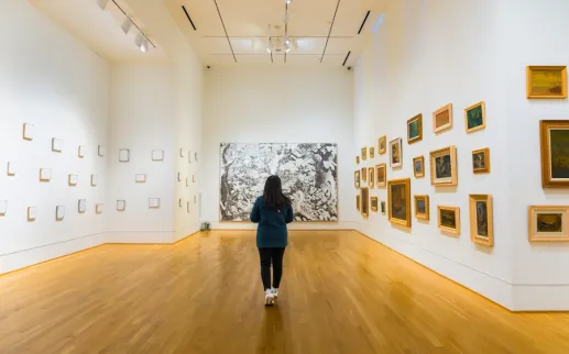 Person walking through bright art gallery in The Phillips Collection with framed works on white walls
