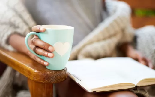 Donna che tiene una tazza e legge un libro