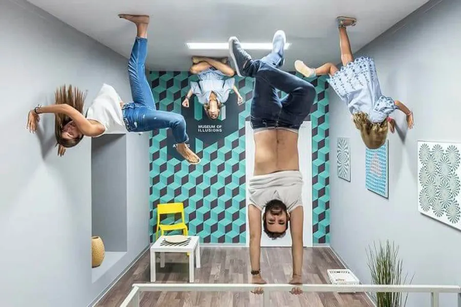 Group of people in a room in what seems they are hanging upside down inside the Museum of Illusions