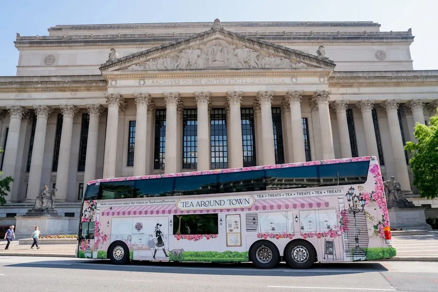 A bus decorated with cherry blossoms passes by the National Archives building. 