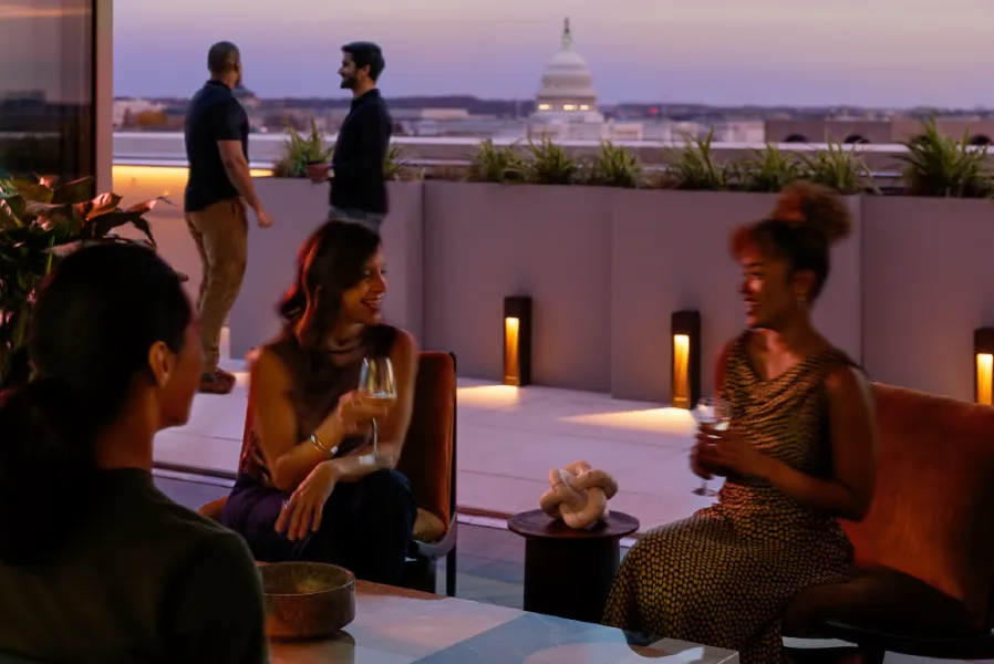 People gathered on a rooftop looking out at the Capitol.