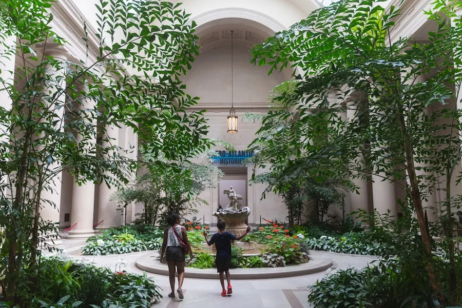 A mother and son walk through a greenery-filled atrium in the National Gallery of Art.
