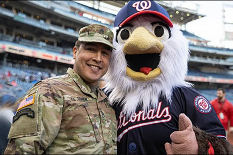A uniformed U.S. Army soldier smiles beside Screech, the Washington Nationals mascot, at Nationals Park in Washington, DC.
