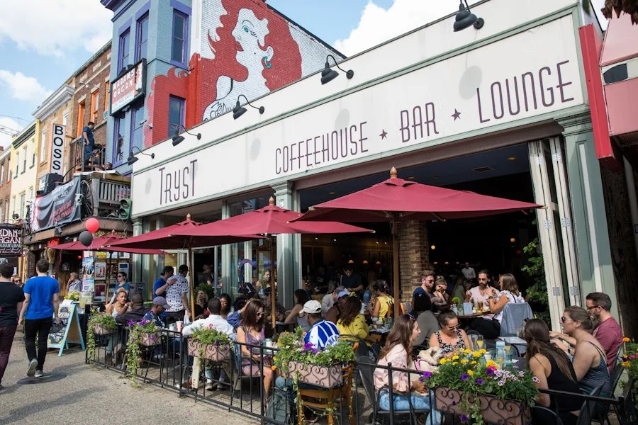 The exterior of Tryst coffeeshop in Adams Morgan, with people dining at tables outside and a mural in the background.