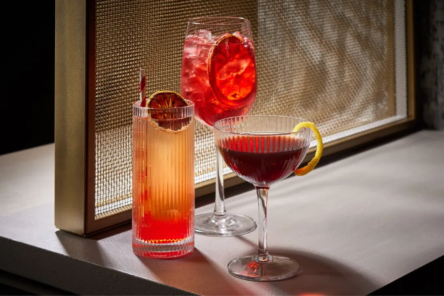Three vibrant cocktails with citrus garnishes on a softly lit table in Washington, DC.