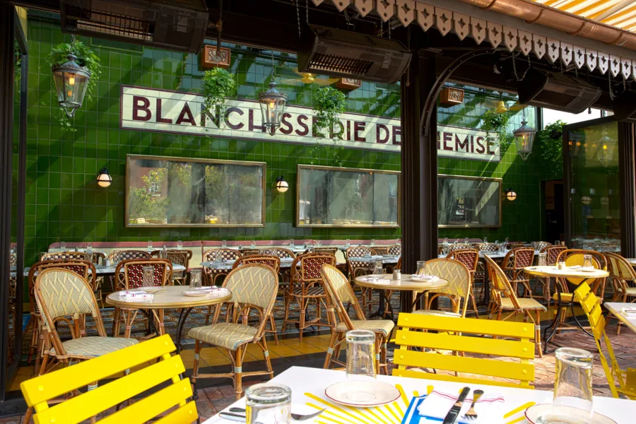 Sunny sidewalk seating outside Le Diplomate in Washington, DC with colorful chairs and vintage Parisian decor.