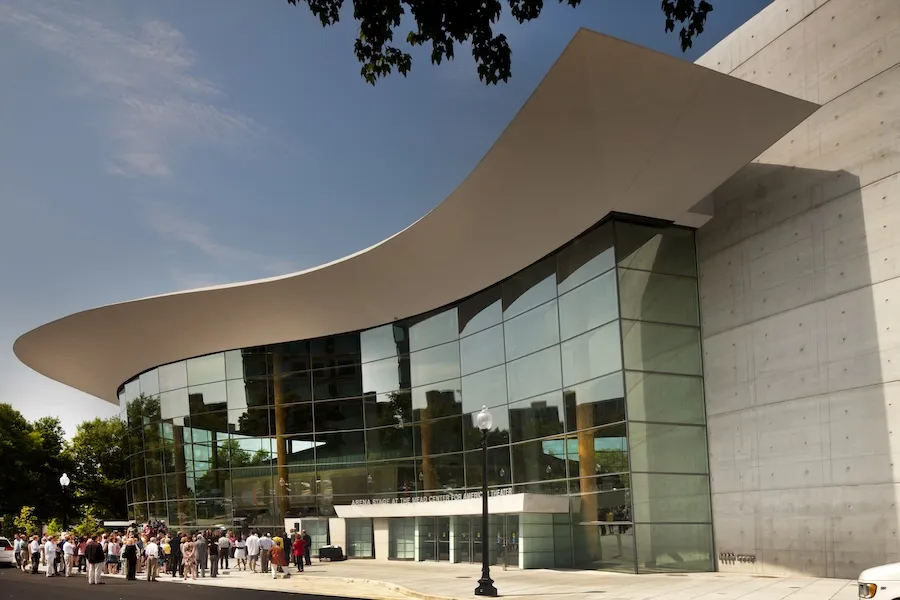 A crowd gathers outside the Arena Stage at the Mead Center under its dramatic curved roof.