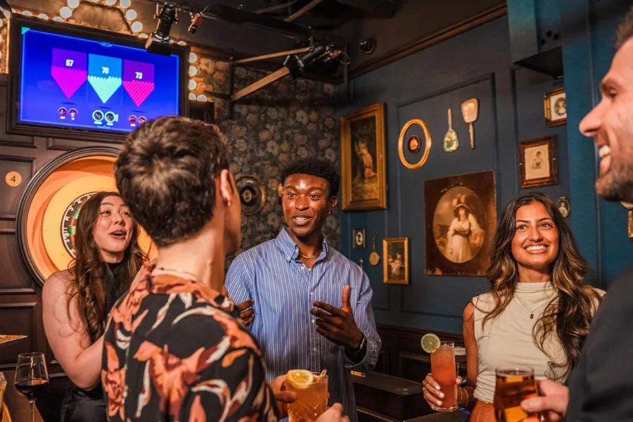 A lively group of friends enjoys drinks and social darts at Flight Club Darts in a vintage-themed setting.