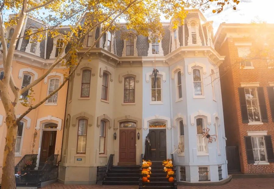 Colorful townhomes in Georgetown in the fall with Halloween decorations adorning the door in the center.