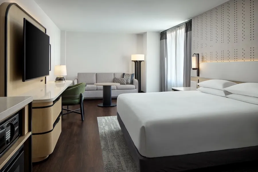 An elegant hotel room with a king sized bed in the center. 
