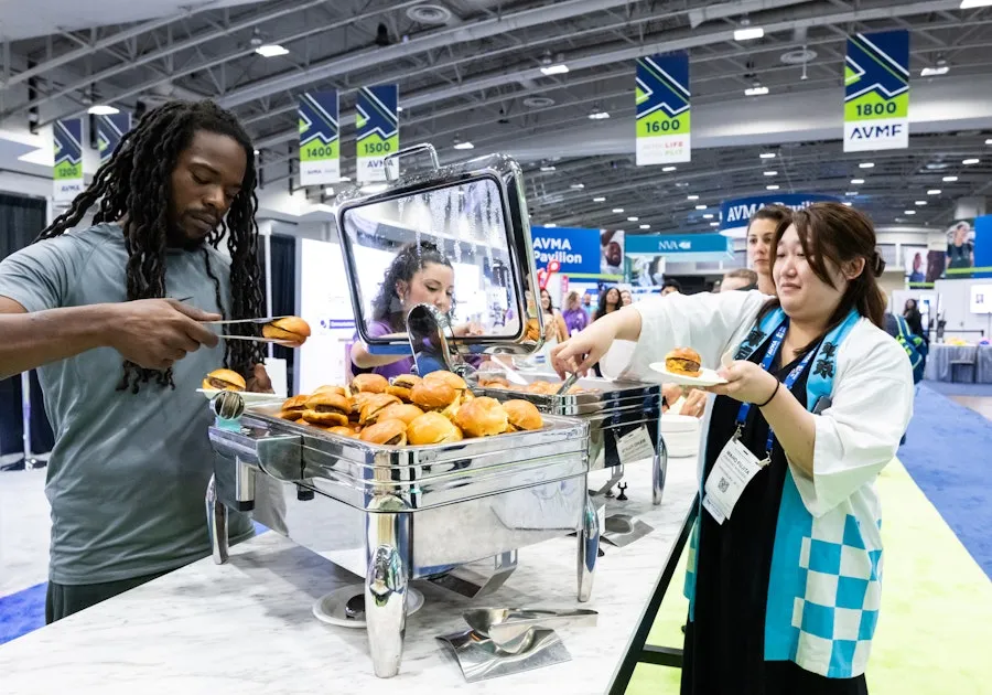People serve themselves sliders from a buffet station at a the Walter E. Washington conference expo hall.