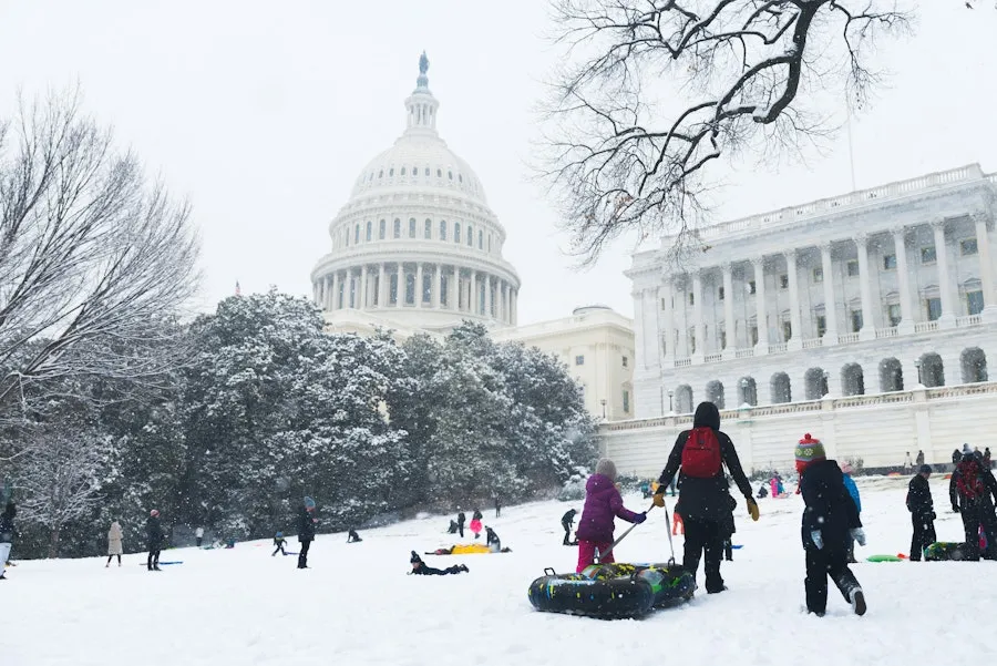Families and children sled down a snowy hill in front of the U.S. Capitol during a winter day in Washington, DC.