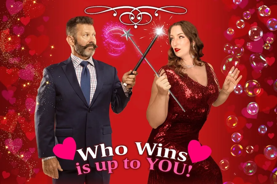 A man and woman face off playfully with magic wands against a festive Valentine’s Day backdrop.