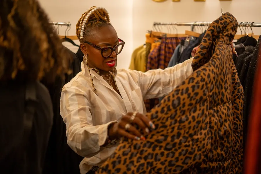 A shopper examines a patterned garment inside a stylish clothing boutique.
