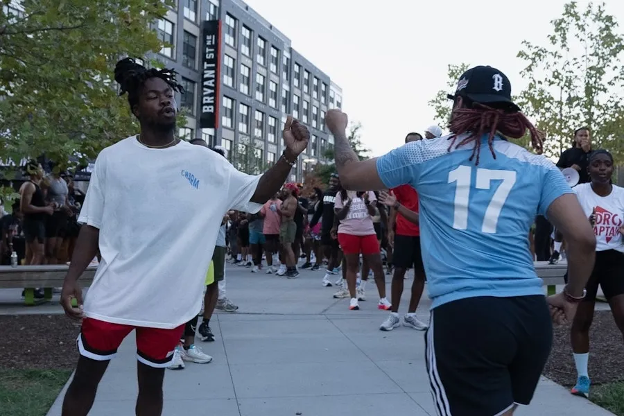 Two runners exchange a celebratory fist bump as a crowd gathers during a community run in DC.