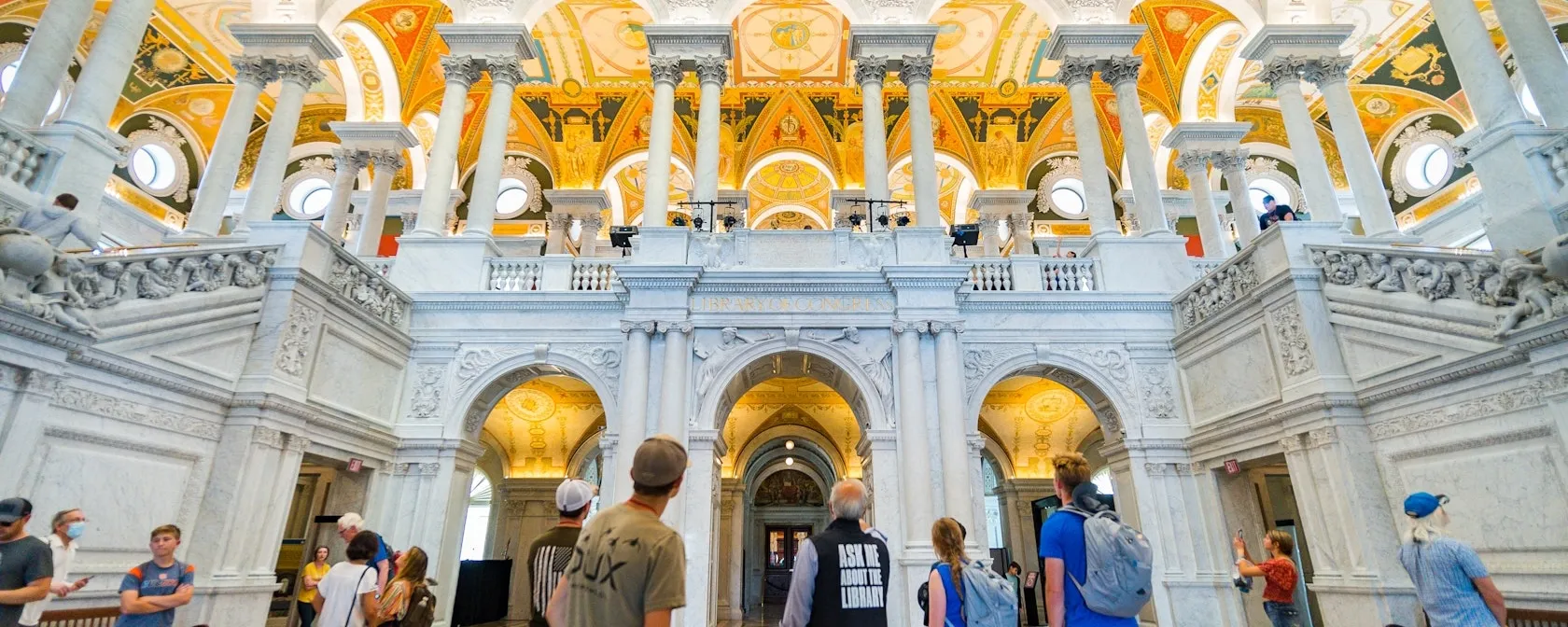 Visitors look up at the ornate columns and golden ceiling inside the Library of Congress Great Hall.