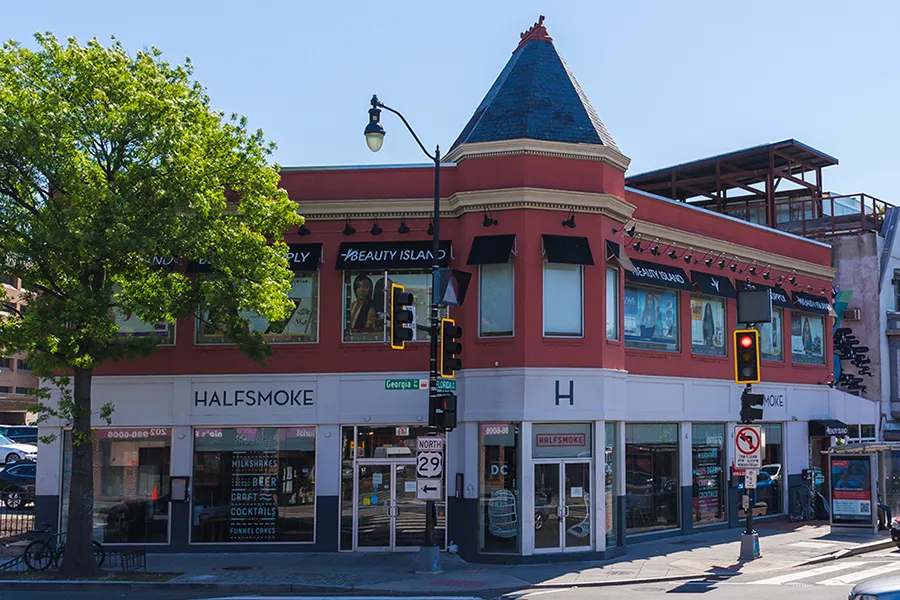 HalfSmoke restaurant on the corner of Florida Avenue and Georgia Avenue NW in Washington, DC, a red-brick building with a turret roof and street traffic lights out front.