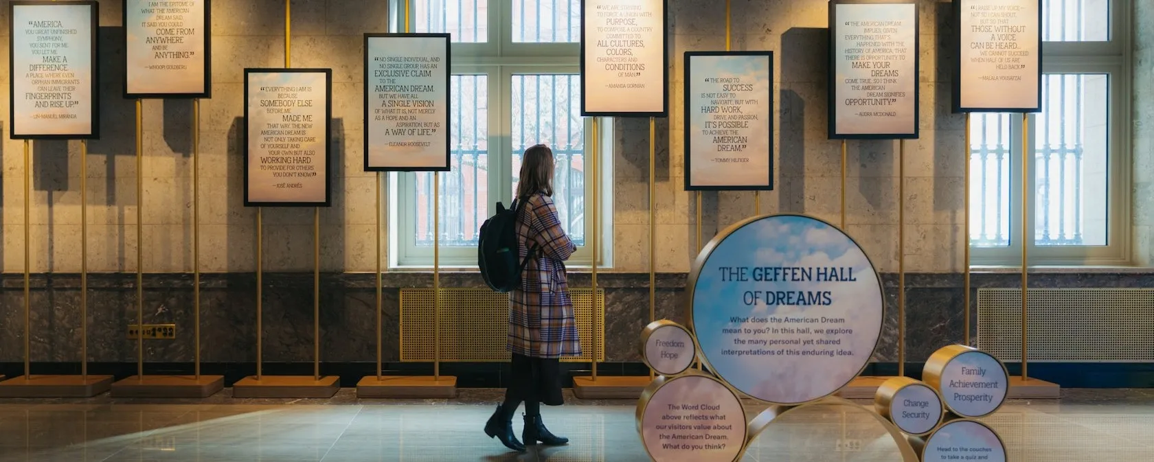 A visitor reads framed quotes in a museum gallery labeled “The Geffen Hall of Dreams.”