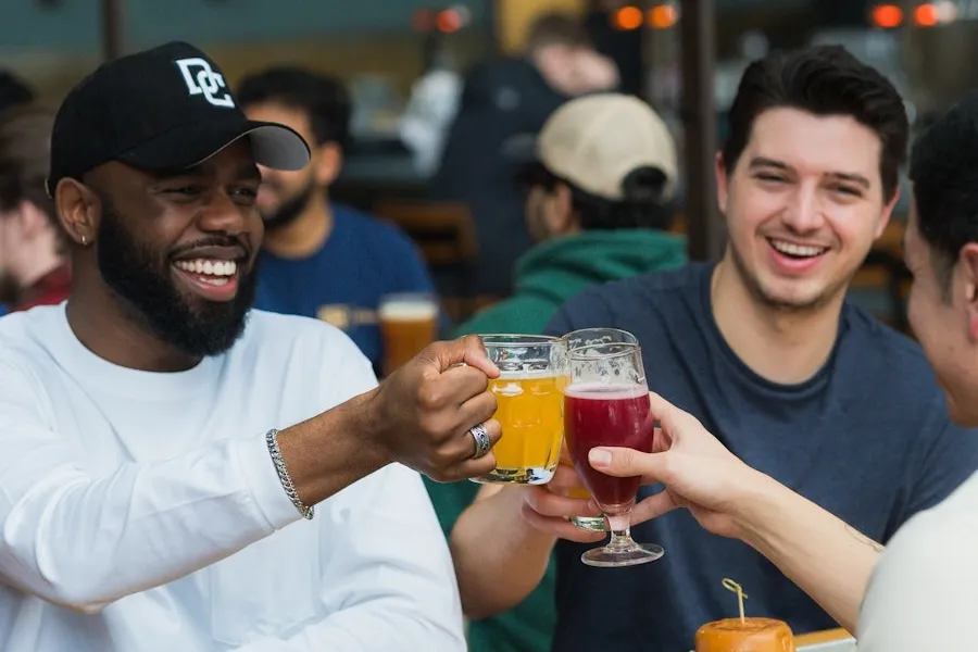Friends clinking beer mugs and glasses, smiling at a beer garden