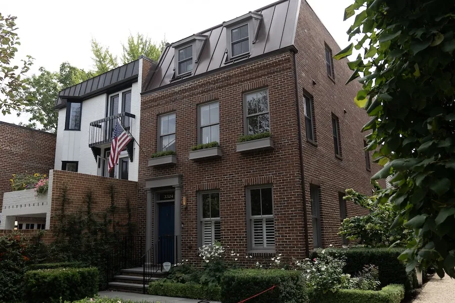 Brick townhouse with bay windows, black awnings and a small front garden