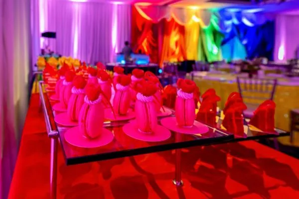 Desserts displayed at Capital Pride’s The Audacity Brunch: In Full Fuchsia, featuring vibrant pink pastries arranged on a table in a ballroom illuminated with colorful rainbow lighting.