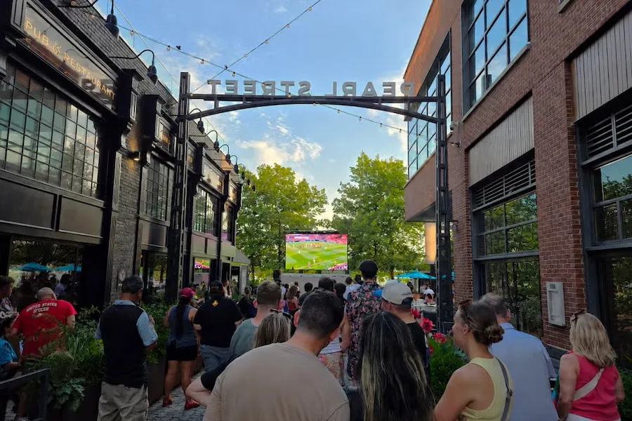 Crowd watching soccer on a screen on a closed-off city street