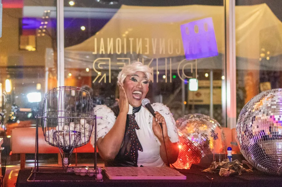 Smiling DJ at a neon-lit table with a disco ball and headphones