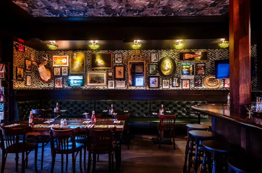 Dimly lit bar with framed wall art and tables and chairs
