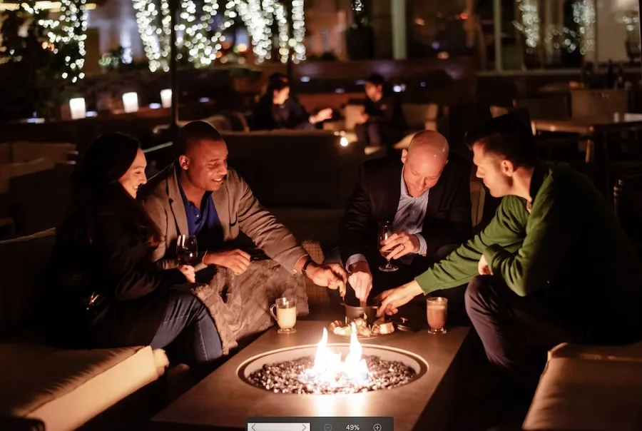 People sitting around a glowing fire pit at night at Blue Duck Tavern