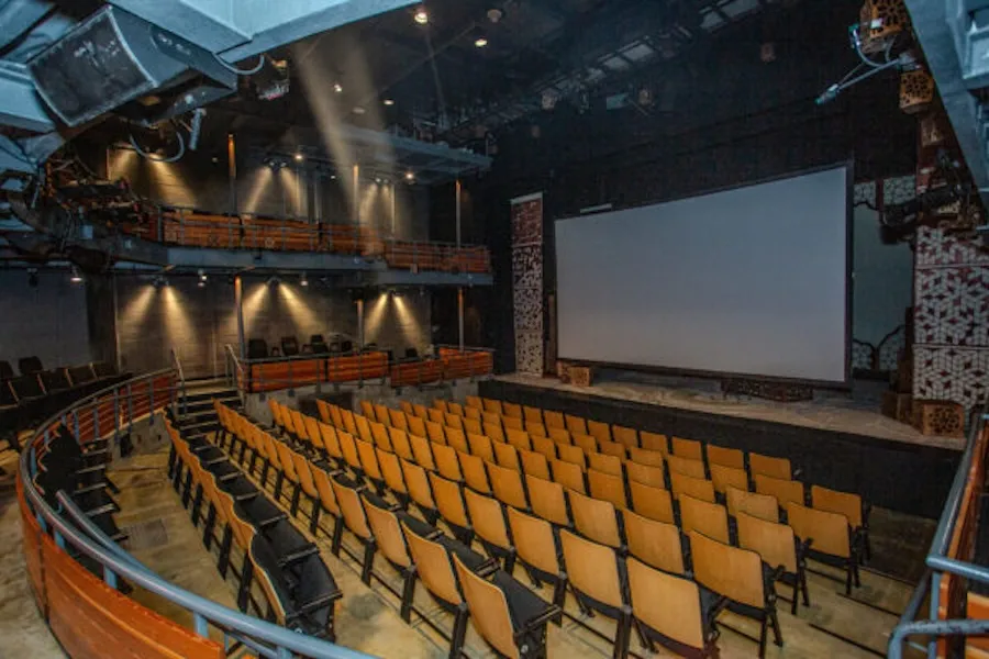 Empty Woolly Mammoth theater with yellow seats facing a large screen