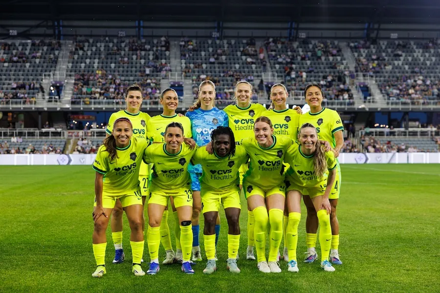 Photo of a soccer team posing in a stadium under bright lights